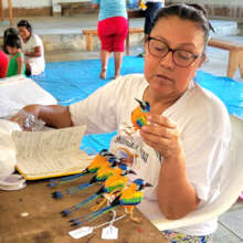 Yully reviewing bird ornaments at artisan workshop