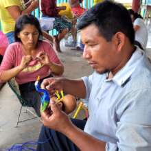 Edson making chambira bird ornament at workshop