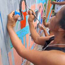 Bora woman painting mural at Brillo Nuevo