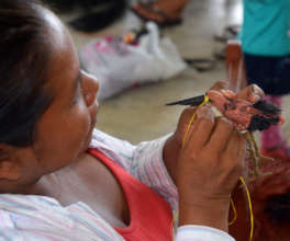 Artisan sewing eye onto tiger heron ornament