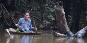 9. Smiling man fishing from dugout canoe