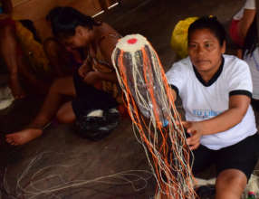 Bora artisan weaving bottle carrier at workshop