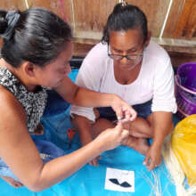 Doilith teaching artisan to make a woven butterfly