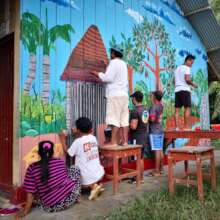 Group painting mural on schoolwall at Brillo Nuevo