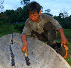 Bora man caulking canoe with copal resin