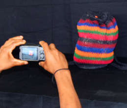 Artisan taking studio photograph of woven bag