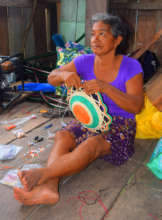 Romelia putting beads on basket