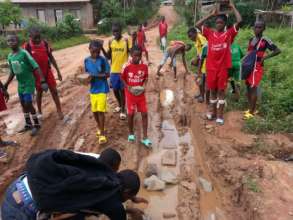 Youth lay stones in the road to improve access