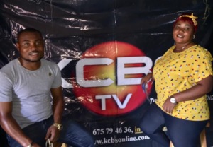 Divine and Nenne sit at the TV station