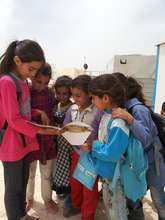 An older girl reads the magazine to the young.