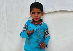 Syrian refugee child outside his family tent