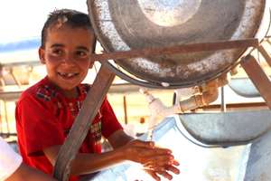 A refugee boy using Mercy Corps provided water