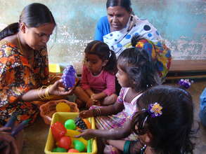 Teacher teaching about fruits to children