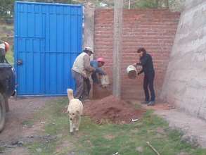 Ruth pouring cement in hole to set the post