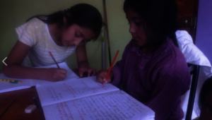 Girls study with siblings during home school
