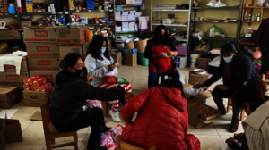 Teachers laugh while they wrap Xmas gifts for girl