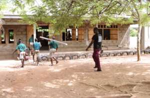 Children carry laptops and equipment into class.