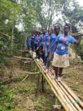 CHWs crossing a bridge to reach a remote village
