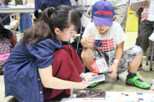 "Maker" kid instructs a "visitor" kid how to play