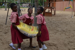 Three enthusiastic girls help carry donations.