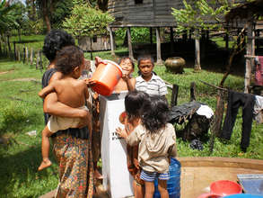 Mother using a bio-sand water filter for her child