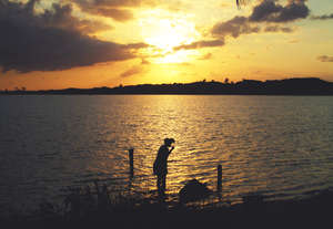 A woman brushes her teeth at sunrise