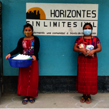 Lucrecia and her sister receiving food baskets