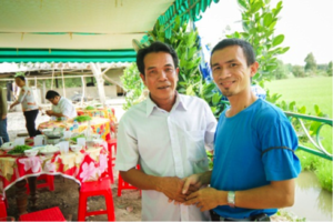 Mr. Son (rt) talks with Mr. Nam outside his home