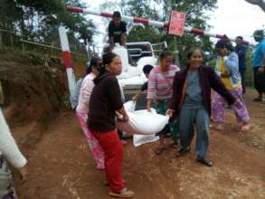 Women help to carry rice sacks into the community