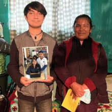 Jesus, with mom, holds a photo of his siblings.