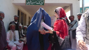 Surrounded by men, a student in a burqa graduates.