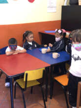 Adorable 3 year-olds help each other finish lunch