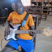 A young guitar student focused on his instrument