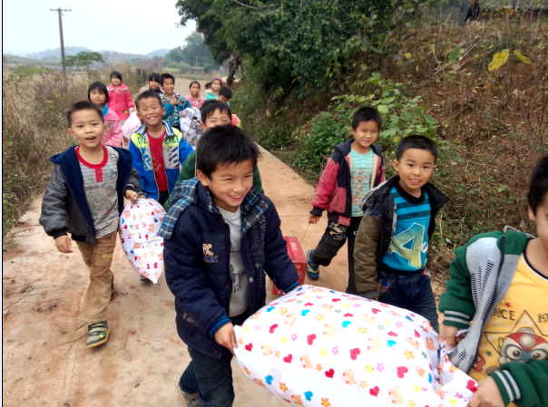 Children helping volunteers carry school supplies