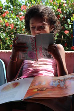 Girl enjoying reading at Ms. Edna's home