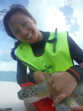 a teen holds a sea turtle waiting for release