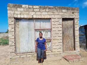 Annah standing in front of her one bedroom house.