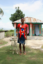 Encise with her goat in front of her home in Haiti
