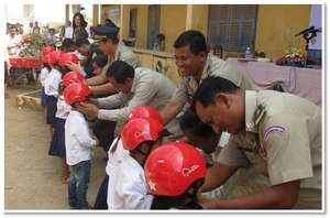 Traffic police fasten helmets on students