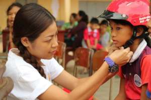 A YARS team member helps a student wear a helmet.