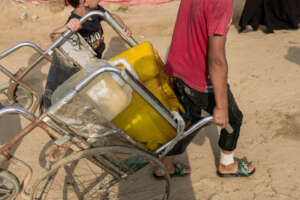Kids carry clean drinking water back to their tent