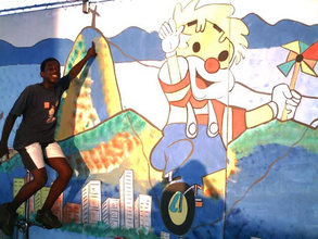 Youth on Unicycle with Mural at the Project