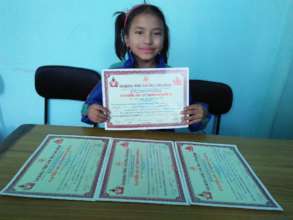 SRIJANA,Class-1 happily displaying certificates .