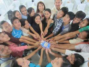 Scholars and an advisor put their hands together