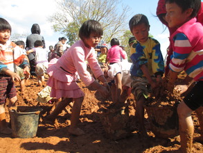 Kachin children helping to mix for mud bricks