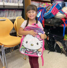 A second grader holding a Hello Kitty backpack