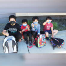 A group of masked children w/ backpacks