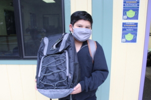 Happy boy with his backpack outside the classroom