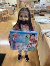 A young girl holding a doctor's playset