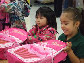 Two girls receive backpacks